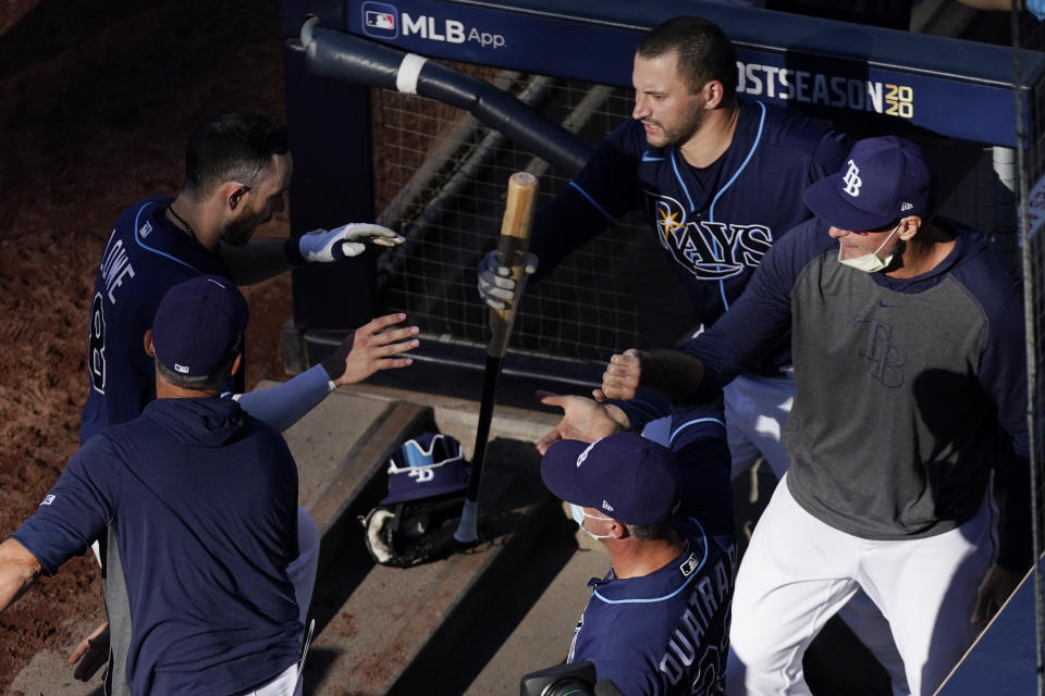Tampa Bay Rays' Brandon Lowe, left, is congratulated after scoring on Willy Adames' RBI double during the second inning in Game 6 of a baseball American League Championship Series against the Houston Astros, Friday, Oct. 16, 2020, in San Diego (AP Photo/Ashley Landis)