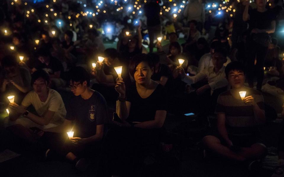 This file photo taken on June 4, 2019 shows people holding candles during a vigil in Hong Kong - ISAAC LAWRENCE/AFP via Getty Images