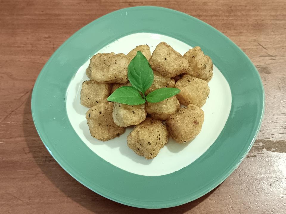 Gnocchi with an herb garnish on a small white and green plate