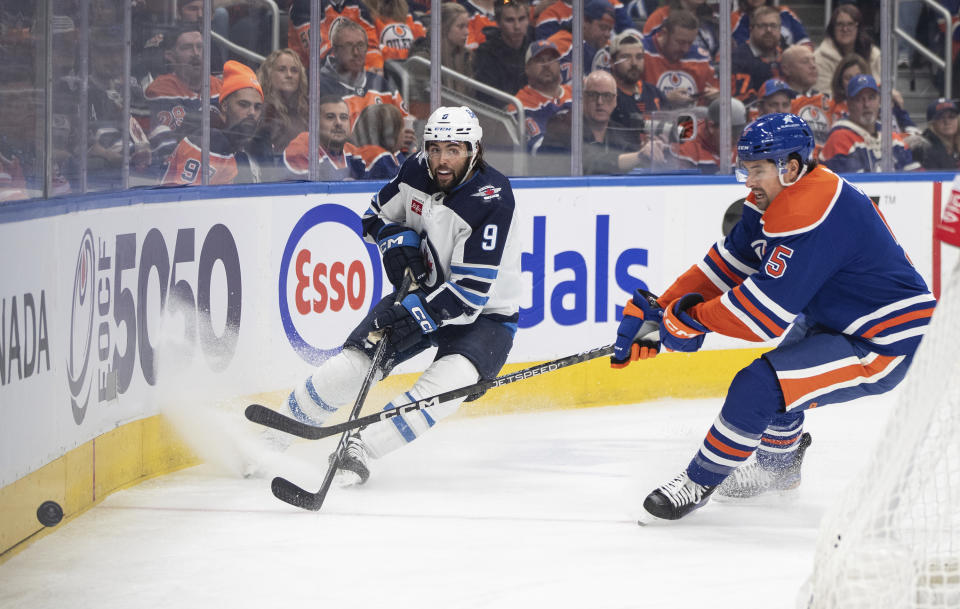 Winnipeg Jets' Alex Iafallo (9) and Edmonton Oilers' Cody Ceci (5) battle for the puck during the first period of an NHL hockey game in Edmonton, Alberta, Saturday, Oct. 21, 2023. (Jason Franson/The Canadian Press via AP)