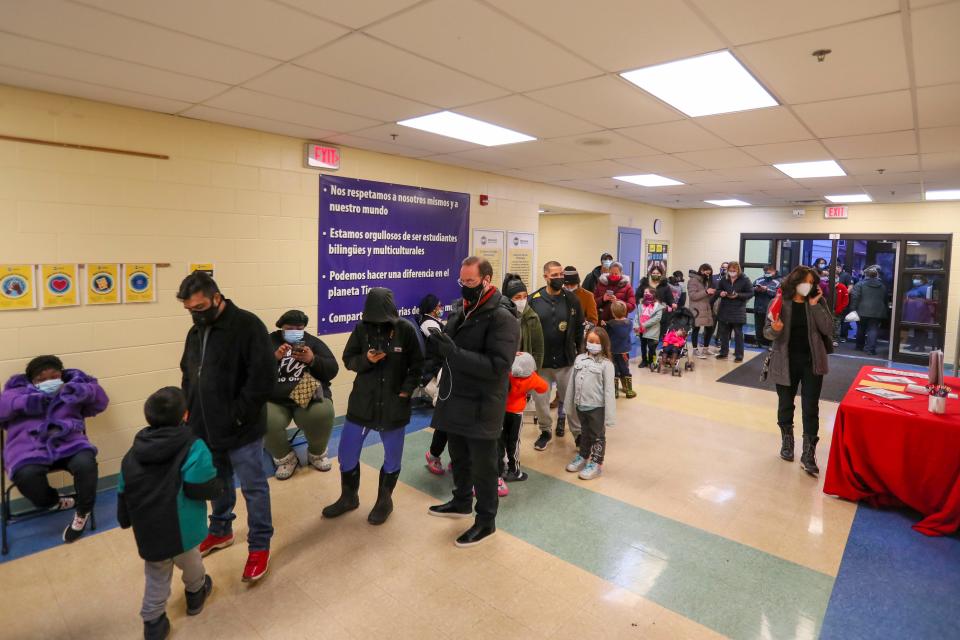 Families wait in line Thursday, Jan. 13, 2022, at Escuela Fratney to receive their COVID-19 vaccine dose in Milwaukee.