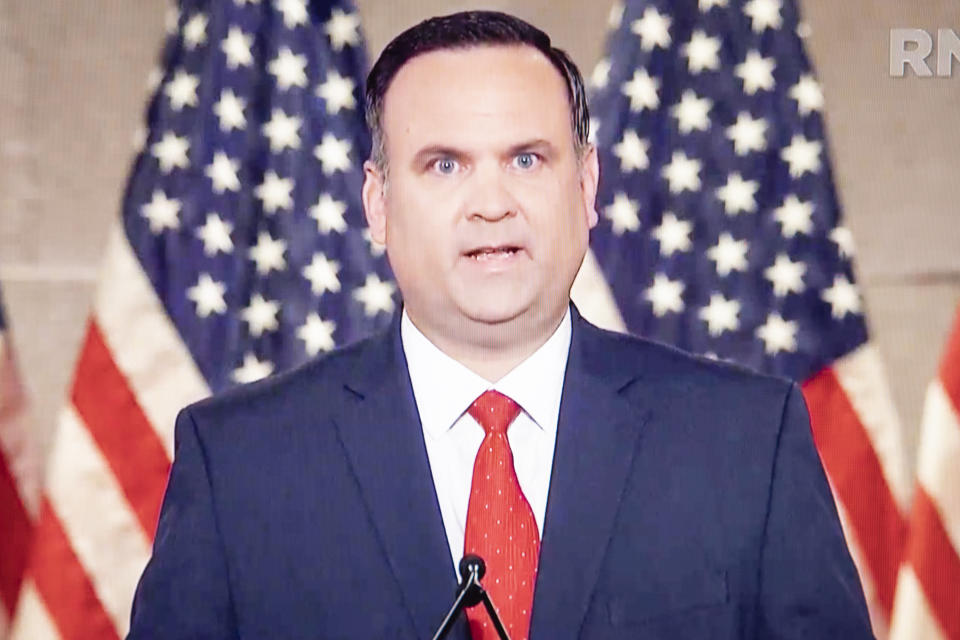 Dan Scavino Jr., White House deputy chief of staff for communications during the Trump administration, stands in front of two American flags..