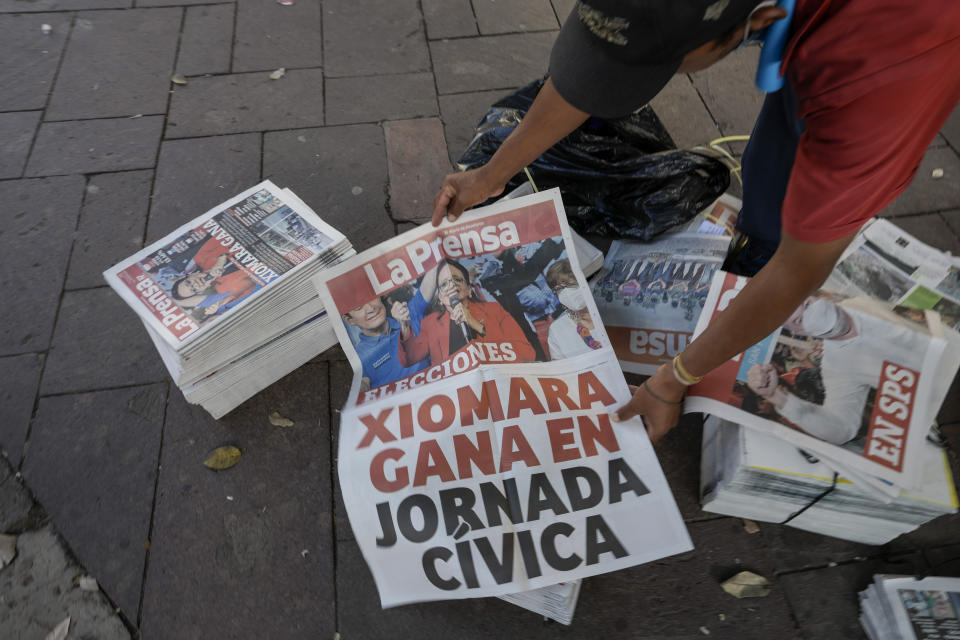 A man shows a poster with a photo of Free Party presidential candidate Xiomara Castro at his newspaper stand after general elections in Tegucigalpa, Honduras, Monday, Nov. 29, 2021. Castro is holding a commanding lead as Hondurans appear poised to remove the conservative National Party after 12 years of continuous rule. (AP Photo/Moises Castillo)