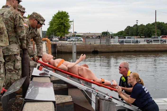 Philadelphia firefighters Capt. Stefani Gorman, marine operations officer, and Thomas Fry, fireboat engineer, deliver a notional victim to mass casualty decontamination personnel assigned to the 140th Chemical Company, California National Guard, at the Navy Yard in Philadelphia July 26. (Capt. Joe Legros/Army)