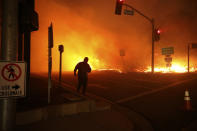 FILE - In this Friday, Oct. 11, 2019 file photo, a bystander watches the Saddleridge fire in Sylmar, Calif. California's largest utility Pacific Gas & Electric Corp pledged to improve communications but reminded state regulators that its "difficult decision" to pre-emptively shut off power to more than 2 million people last week may have prevented deadly wildfires. (AP Photo/David Swanson, File)