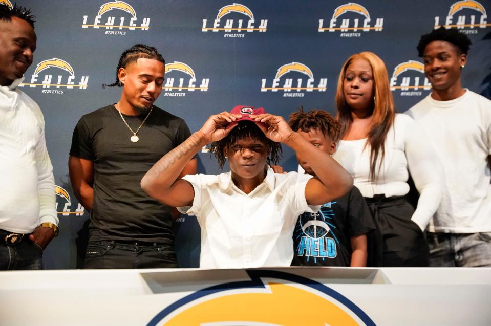 Kelton Henderson puts on his University of South Carolina hat after signing while surrounded by his family at Lehigh Senior High School in Lehigh Acres on Wednesday, Dec. 21, 2022. 