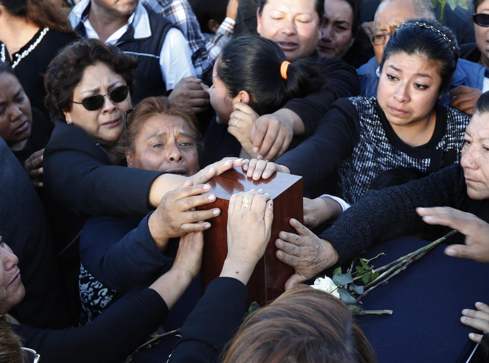 Relatives and friends touch the urn with ashes of opposition Puebla state Gov. Martha Erika Alonso during a farewell ceremony in Puebla City, southeast of Mexico, Tuesday, Dec. 25, 2018. Mexico has invited experts from the U.S. National Transportation Safety Board to investigate a helicopter crash that killed the governor, her husband, two pilots and a third passenger. (AP Photo/Marco Ugarte)