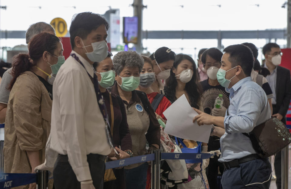 Airport officials speak with tourists from Wuhan, China, a they prepare to take a charter flight back to Wuhan at the Suvarnabhumi airport, Bangkok, Thailand, Friday, Jan. 31, 2020. A group of Chinese tourists who have been trapped in Thailand since Wuhan was locked down due to an outbreak of new virus returned to China on Friday. (AP Photo/Gemunu Amarasinghe)