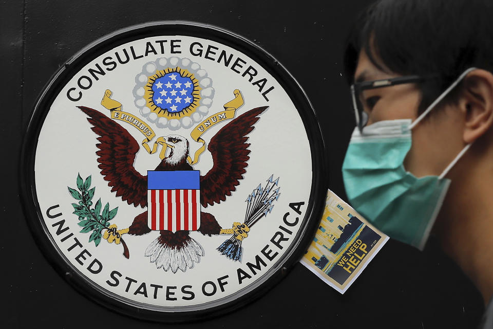 A protester walks by the U.S. emblem with "Help" message stuck during a protest outside the U.S. Consulate in Hong Kong, Wednesday, June 26, 2019. Hong Kong activists opposed to contentious extradition legislation on Wednesday called on leaders of the U.S., the European Union and others to raise the issue with Chinese President Xi Jinping at this week's G-20 summit in Japan. (AP Photo/Kin Cheung)