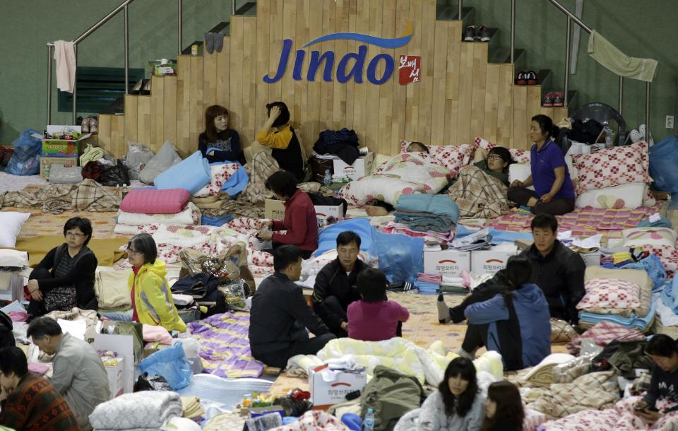 Relatives of passengers aboard the sunken ferry Sewol wait for news on their missing loved ones at a gymnasium in Jindo, south of Seoul, South Korea, Monday, April 21, 2014. Divers continued the grim work of recovering bodies from inside the sunken South Korean ferry Monday, securing a new entryway into the wreck, as a newly released transcript showed the ship was crippled by confusion and indecision well after it began listing. The transcript suggests that the chaos may have added to a death toll that could eventually exceed 300. (AP Photo/Lee Jin-man)