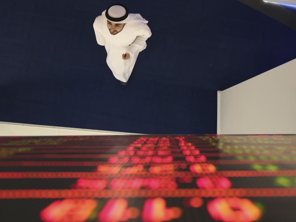 An Emirati trader checks the stocks on the screen at the Dubai Financial Market in Dubai, United Arab Emirates, Sunday, March 8, 2020. Stocks markets in the Mideast suffered sharp drops in early trading Sunday over fears about the new coronavirus and demand in crude oil falling amid a failure by OPEC and allied nations to cut production. (AP Photo/Kamran Jebreili)