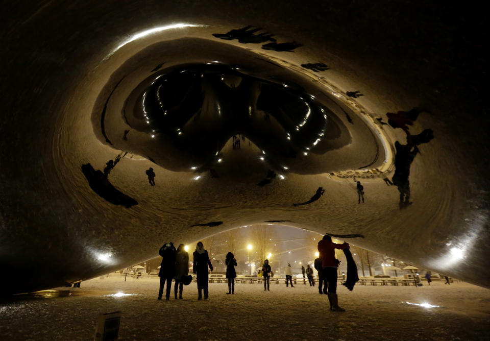 People enjoy a snow-covered Cloud Gate at Millennium Park in downtown Chicago, which became a great photo opportunity for visitors, Wednesday, Jan. 1, 2014. As much as 9 inches of snow has fallen in some parts of the Chicago area since New Year's Eve, and a second wave is expected to dump several more inches by Thursday. (AP Photo/Nam Y. Huh)