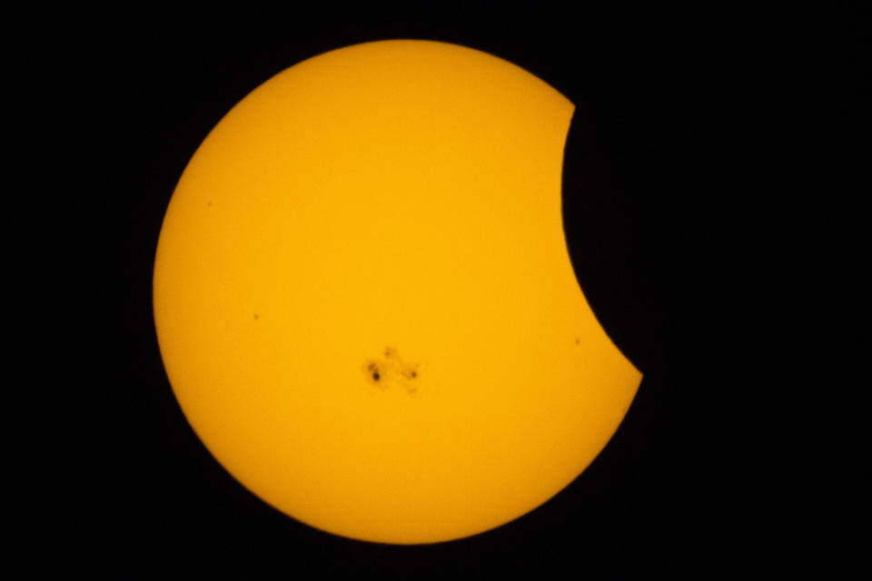 partial solar eclipse with the moon appearing to take a 'bite' out of the sun.  A large sunspot is visible on the surface.