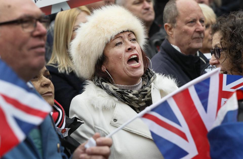 FILE - In this Wednesday, Nov. 23, 2016 file photo, pro-Brexit demonstrators wave flags outside the Parliament in London. The protest was timed to coincide with a statement by treasury chief Philip Hammond in the first budget update since the U.K. voted to leave the European Union. Nigel Farage, a leader of the Brexit campaign says, "What the little people did ... was they rejected the multinationals, they rejected the merchant banks, they rejected big politics and they said actually, we want our country back." (AP Photo/Kirsty Wigglesworth)