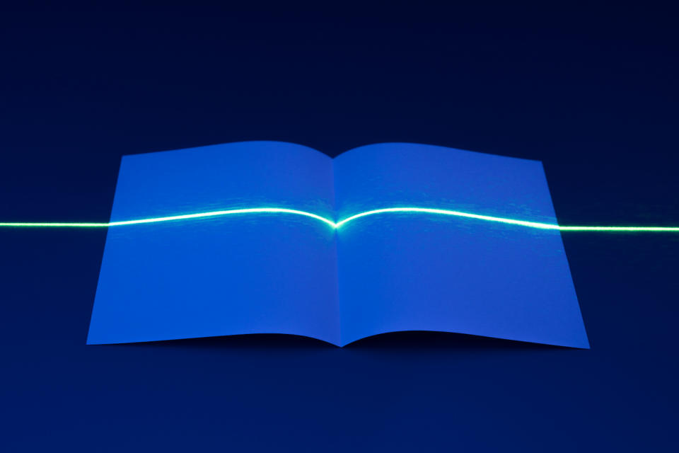 Laser Light Interrupted by Unfolded Book Shape of Paper.