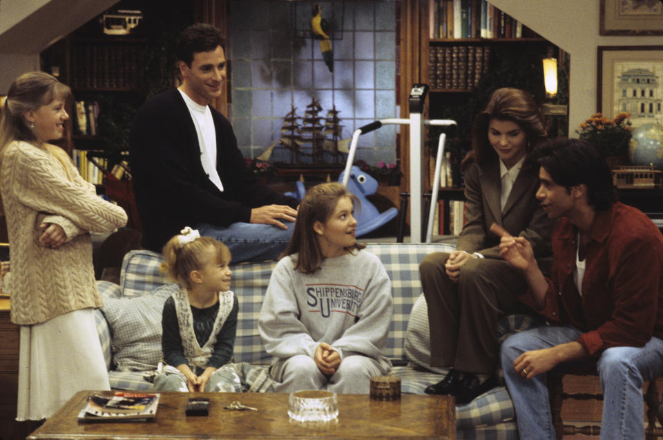 the cast sitting in the living room during a scene