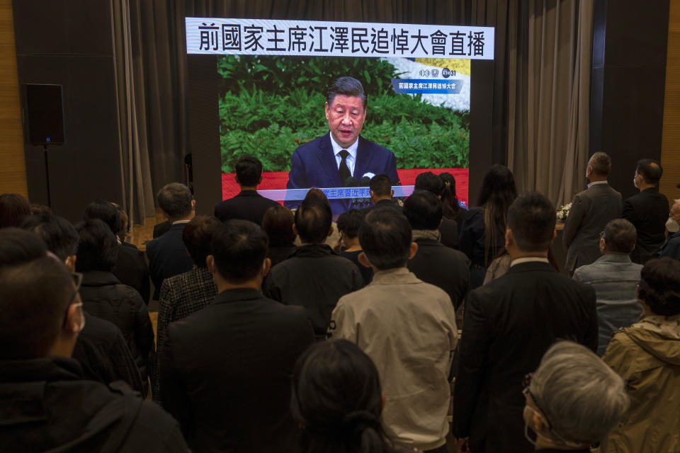 Residents watch a live broadcast of the memorial service for late former Chinese President Jiang Zemin where Chinese President Xi Jinping makes a speech on screen at a community center in Hong Kong, Tuesday, Dec. 6, 2022. A formal memorial service was held Tuesday at the Great Hall of the People, the seat of the ceremonial legislature in the center of Beijing. Words on screen read "Former Chairman Jiang Zemin memorial live broadcast." (AP Photo/Vernon Yuen)