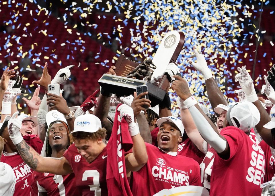Alabama players celebrate with the championship trophy on Dec. 2, 2023, at Mercedes-Benz Stadium. Alabama defeated Georgia 27-24 to claim the SEC championship.