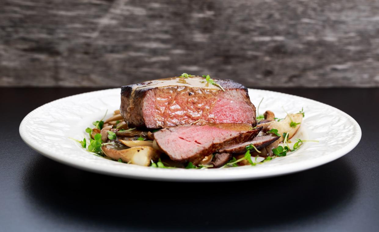 Tasty Beef Mignon sliced steak with mushrooms and herbs on plate