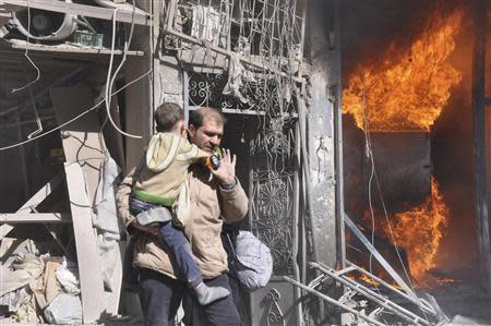 A man rescues a child near a fire after what activists said was shelling from forces loyal to Syria's President Bashar Al-Assad in Aleppo's Bustan al-Qasr neighbourhood, February 8, 2014. REUTERS/Yaman Al Halabi