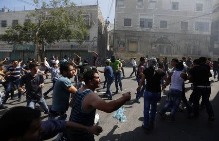 Palestinian protesters hurl stones toward Palestinian riot police trying to stop the protesters from clashing with Israeli troops, during a protest against the Israeli offensive in Gaza, in the West Bank city of Hebron August 22, 2014. REUTERS/Mohamad Torokman