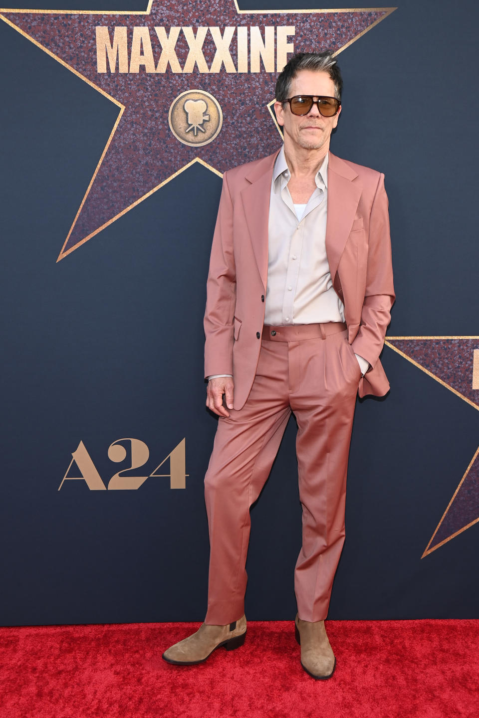 Kevin Bacon is wearing a stylish suit with sunglasses and suede shoes