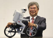 Murata Manufacturing Co Ltd President Tsuneo Murata poses with his company's bicycle-riding robot "Murata Seisaku-kun" after an interview with Reuters on the sidelines of CEATEC JAPAN 2012 electronics show in Chiba, east of Tokyo, October 2, 2012. Anti-Japanese sentiment in China, falling prices and growing competition from a South Korean rival are just a few of the challenges faced by Murata, which supplies Apple Inc with components for its iPhone 5. But even with those challenges, Murata, said on Tuesday the company is forecasting stronger demand from smartphone makers in the July to September quarter and that its factories were operating at full capacity. To match Interview MURATA-INTERVIEW/ REUTERS/Yuriko Nakao (JAPAN - Tags: TRANSPORT BUSINESS EMPLOYMENT)