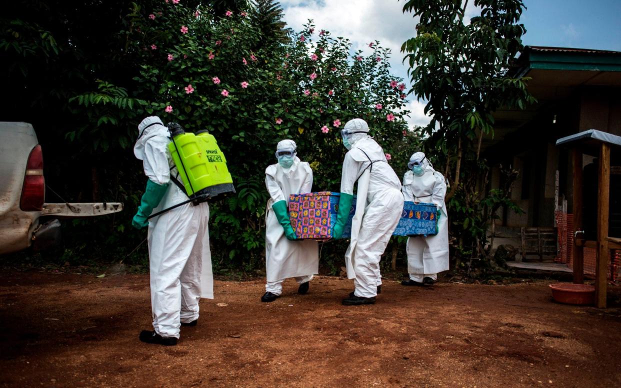 Workers carry the coffin of an Ebola victim in DRC - John Wessels/AFP