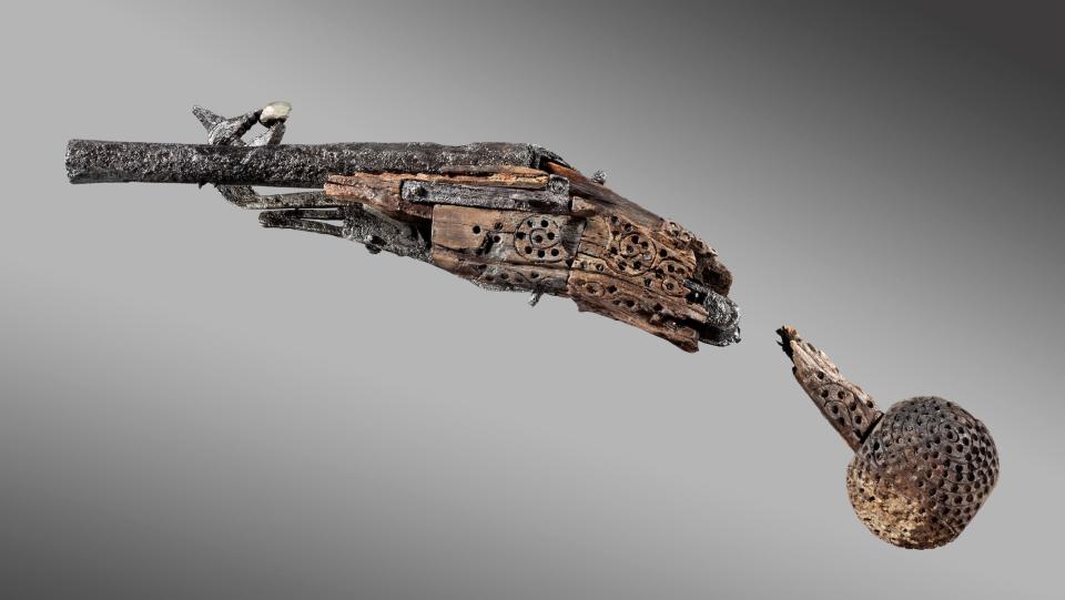 ancient pistol made of gnarled iron with engraved wooden casing and broken wooden handle
