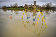 Children's playground equipment pokes out from floodwater surrounding Tewkesbury Abbey, where flood watches are in place with more wet weather expected in the coming days.