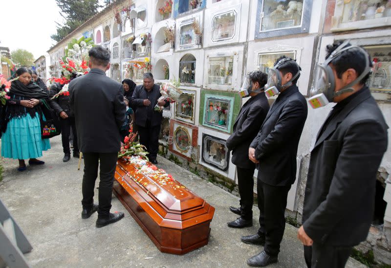 FILE PHOTO: Pallbearers wear gas masks to protect themselves from the coronavirus disease (COVID-19) participate in a burial in La Paz