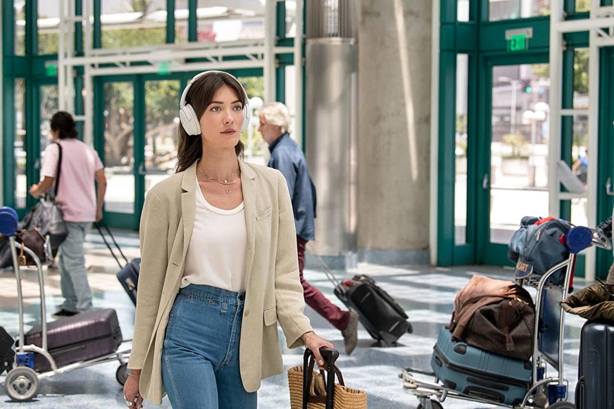 Woman in airport wearing white headphones (Photo: Bose)
