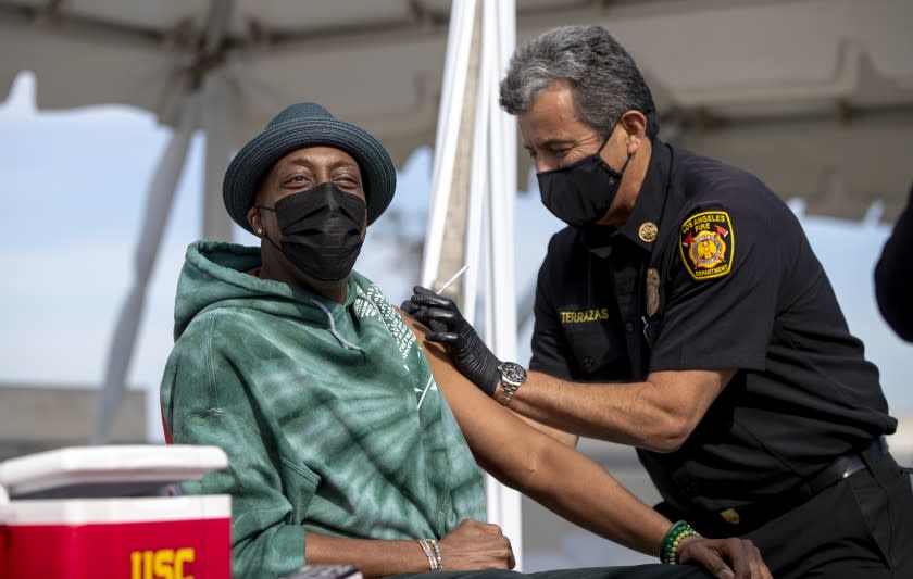 LOS ANGELES, CA - MARCH 24, 2021: Los Angeles Fire Chief Ralph Terrazas gives a vaccine shot to Arsenio Hall on the rooftop of parking structure at USC as a part of a vaccination awareness event at USC on March 24, 2021 in Los Angeles, California.(Gina Ferazzi / Los Angeles Times)