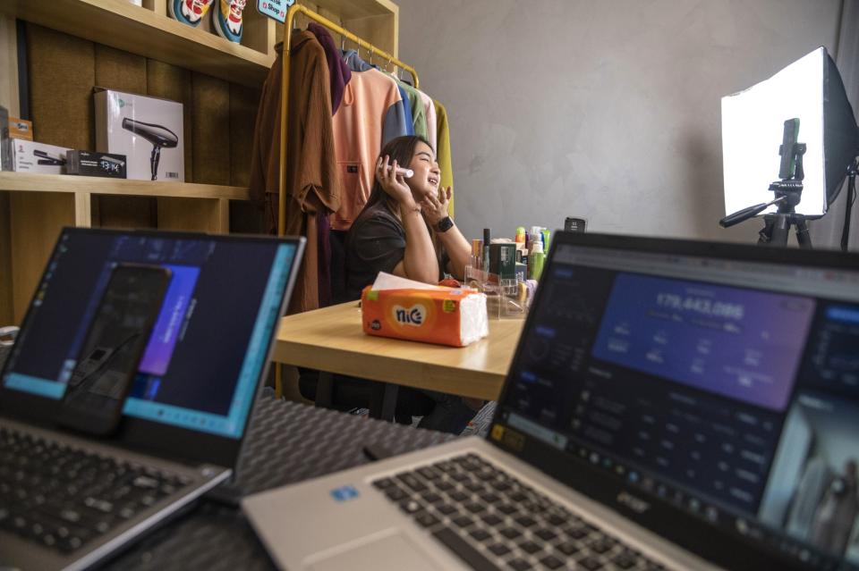 A DCT Agency host promotes products while a staff member monitors statistics. (Rosa Panggabean/Bloomberg)