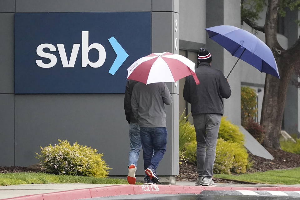People walk past a Silicon Valley Bank sign at the company's headquarters in Santa Clara, Calif., Friday, March 10, 2023. The Federal Deposit Insurance Corporation is seizing the assets of Silicon Valley Bank, marking the largest bank failure since Washington Mutual during the height of the 2008 financial crisis. The FDIC ordered the closure of Silicon Valley Bank and immediately took position of all deposits at the bank Friday. (AP Photo/Jeff Chiu)