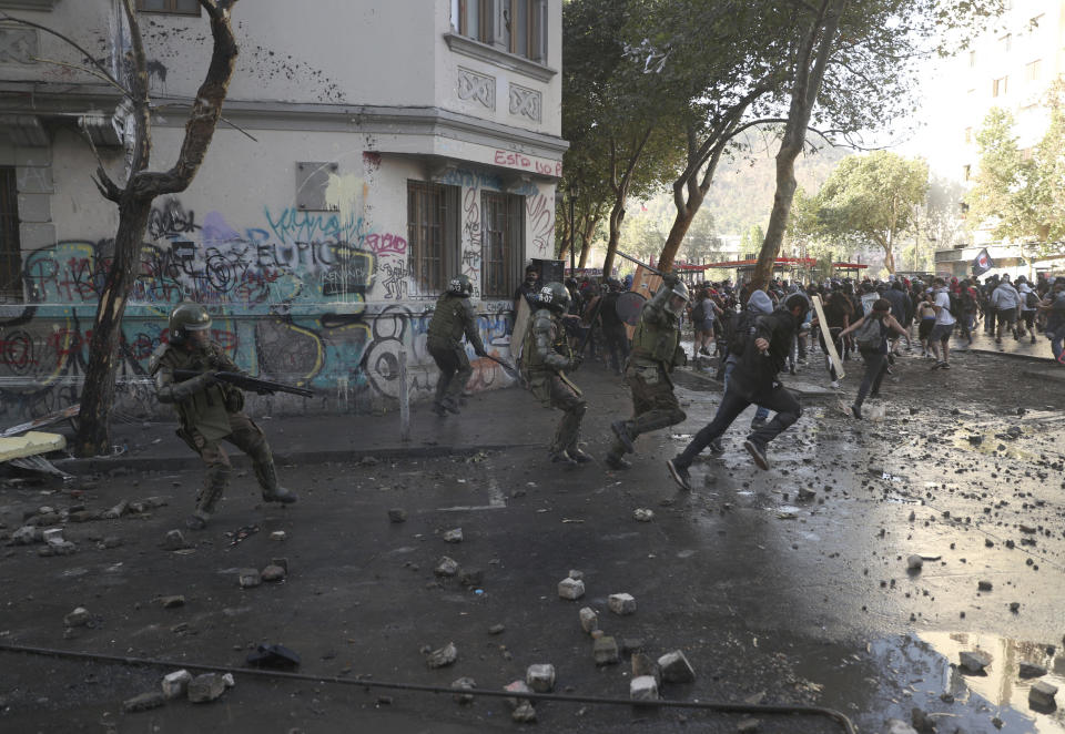 Police charge anti-government demonstrators during protests in Santiago, Chile, Tuesday, Nov. 19, 2019. Chile has been facing weeks of unrest, triggered by a relatively minor increase in subway fares. The protests have shaken a nation noted for economic stability over the past decades, which has seen steadily declining poverty despite persistent high rates of inequality. (AP Photo/Esteban Felix)