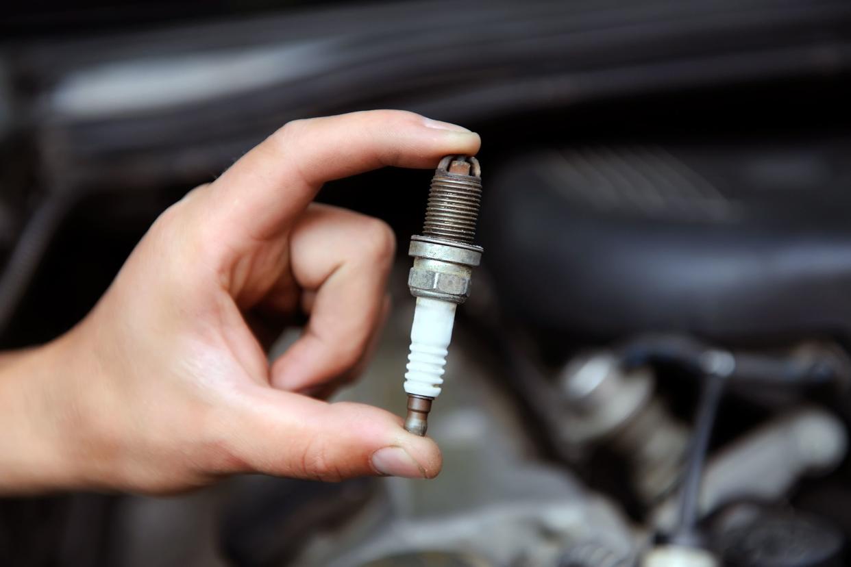 auto mechanic holds an spark plug