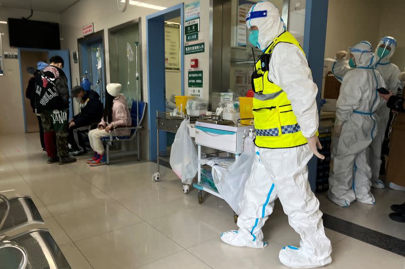 FOTO DE ARCHIVO. Un miembro del personal de seguridad con traje de protección vigila mientras los trabajadores médicos atienden a los pacientes en el departamento de fiebre del Hospital Tongji, un importante centro para pacientes de la enfermedad por coronavirus (COVID-19), en Wuhan, provincia de Hubei, China