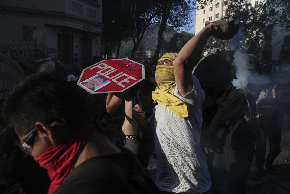 Anti-government protesters clash with police in Santiago, Chile, Monday, Nov. 18, 2019. According to the Medical College of Chile at least 230 people have lost sight after being shot in an eye in the last month while participating in the demonstrations over inequality and better social services. (AP Photo/Esteban Felix)