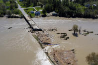 In this Wednesday, May 20, 2020, photo, people survey the flood damage to the Curtis Road Bridge in Edenville, Mich., over the Tittabawassee River. The bridge sits just south of Wixom Lake where the dams failed. (Neil Blake/The Grand Rapids Press via AP)