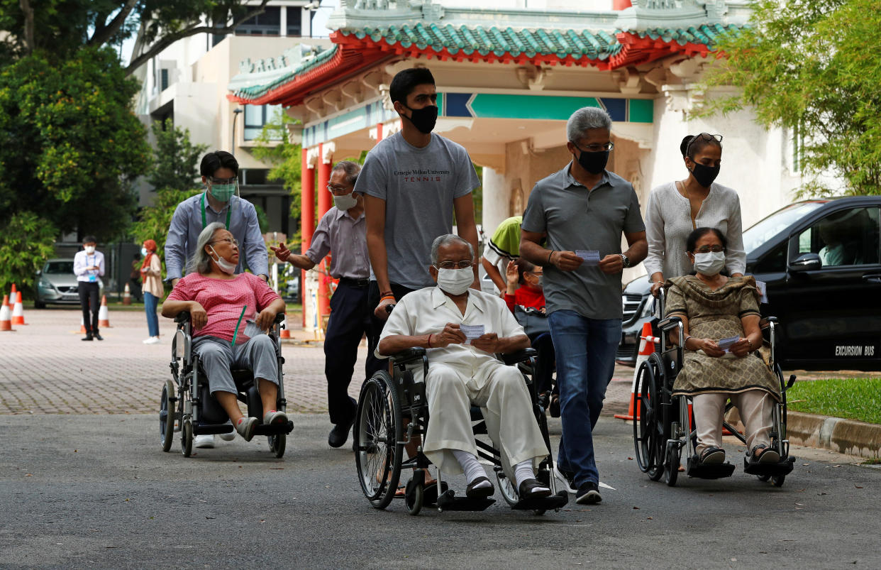 Wheelchair-bound voters arrive at a polling station at a time band allocated to seniors and elders as part of preventive measures against the coronavirus disease (COVID-19) outbreak, during the general election in Singapore July 10, 2020.  REUTERS/Edgar Su