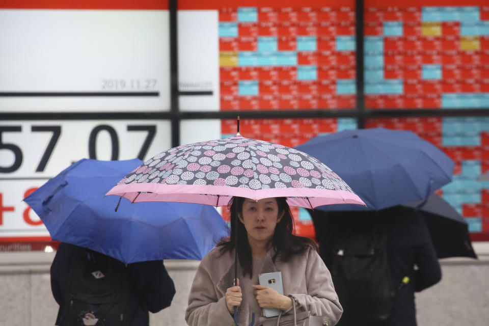 People walk by an electronic stock board of a securities firm in Tokyo, Wednesday, Nov. 27, 2019. Shares were mostly higher in Asia on Wednesday after a fresh set of record highs on Wall Street, spurred by encouraging signs on trade talks between the U.S. and China. (AP Photo/Koji Sasahara)