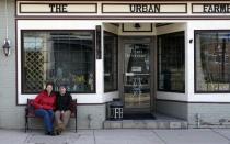 Michael and Lurie Portanova sit in front of their commercial property in Jersey Shore, Pa. on Sunday March 23, 2014. The couple bought the buildings with the intention of restoring their historical details and opening a cafe and canoe rental business. But with an annual scaling back of government subsidies for flood insurance, Michael says, "We'd have to let it go back to the bank and walk away from it." (AP Photo/Ralph Wilson)