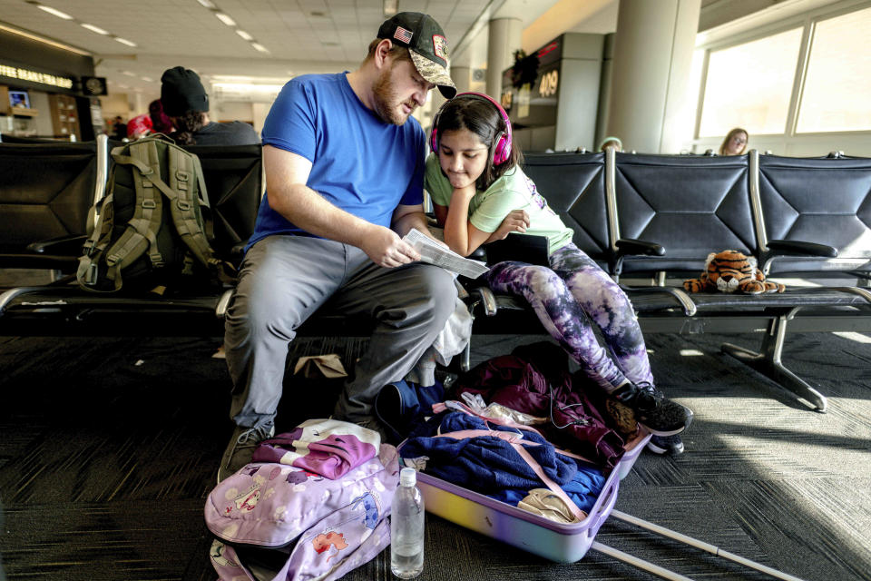 Aaron Banks and daugther, Carmen, 11, look over their boarding pass after their flight to Dallas is delayed at Ontario International Airport in Ontario, Calif. on Friday, Dec. 23, 2022. (Watchara Phomicinda/The Orange County Register via AP)