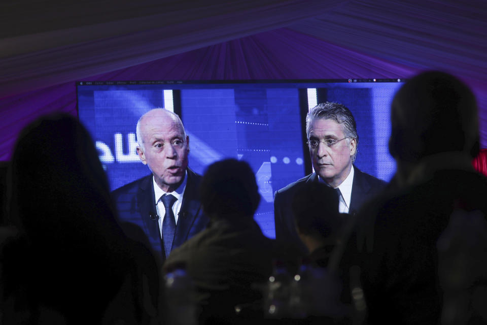 CORRECTS POSITION - People watch a televised debate between presidential candidates Kais Saied, left, and Nabil Karoui, on the last day of campaigning before the second round of the presidential elections, in Tunis, Tunisia, Friday, Oct. 11, 2019. (AP Photo/Mosa'ab Elshamy)