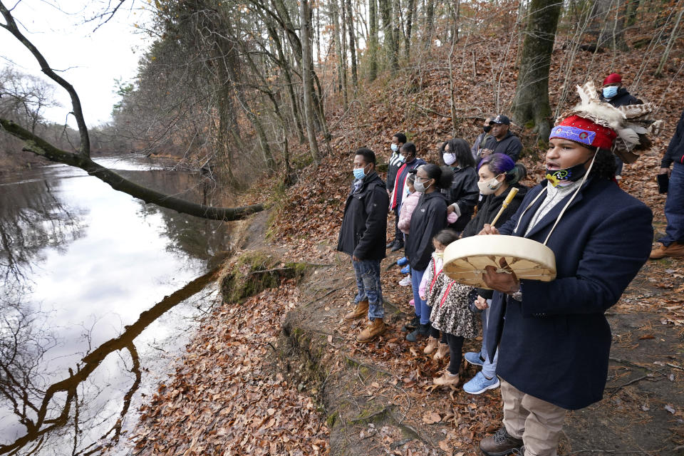 Larry Fisher, chief sachem of the Mattakeeset Massachuset tribe, right, leads other tribal members in a traditional song honoring their land and ancestry along the Taunton River at Titicut Indian Reservation, Friday, Nov. 27, 2020, in Bridgewater, Mass. A rift has been widening between Native American groups in New England over a federal reservation south of Boston where one tribe is planning to build a $1 billion casino. The Mattakeeset Massachuset tribe contend the Mashpee Wampanoag tribe doesn't have exclusive claim to the lands under their planned First Light casino in the city of Taunton, as they've argued for years. (AP Photo/Elise Amendola)