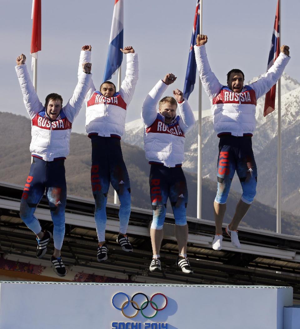 The team from Russia RUS-1, with Alexander Zubkov, Alexey Negodaylo, Dmitry Trunenkov, and Alexey Voevoda, jump onto the medal stand after they won the gold medal during the men's four-man bobsled competition final at the 2014 Winter Olympics, Sunday, Feb. 23, 2014, in Krasnaya Polyana, Russia. (AP Photo/Michael Sohn)