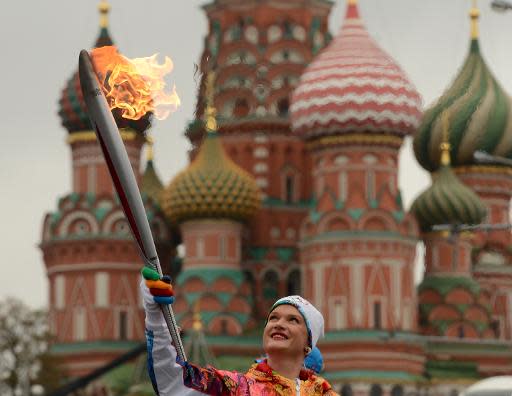 Three-time world champion and two-time Olympic champion in gymnastics, Svetlana Khorkina, carries the Olympic torch in front of St.Basil's cathedral just outside the Red Square in Moscow, on October 7, 2013