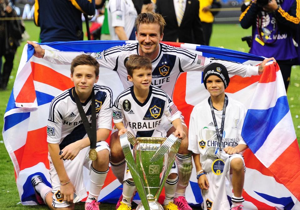 David Beckham poses with his sons Brooklyn (L), Cruz (C) and Romeo and the MLS Trophy after the Los Angeles Galaxy beat Houston Dynamo 3-1 in the Major League Soccer (MLS) Cup, December 1, 2012 in Carson,.California. It was Beckham's last game with the Galaxy.