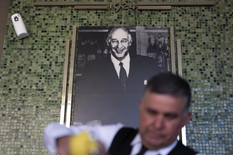 Salad Master Efrain Montoya prepares a Caesar salad in front of an image of the inventor of the salad, Caesar Cardini, at Ceasar's restaurant Thursday, June 27, 2024, in Tijuana, Mexico. Caesar salad has something to celebrate: It's turning 100. Italian immigrant Caesar Cardini is said to have invented the dish on July 4, 1924, at his restaurant, Caesar's Place, in Tijuana, Mexico. (AP Photo/Gregory Bull)